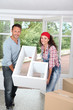 Couple holding furniture in their new home