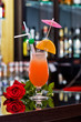 Tequila sunrise cocktail and red rose.