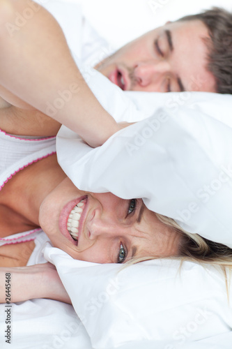 Photo: stressed woman lying on the bed with her boyfriend snoring stressed woman lying on the bed with her boyfriend snoring