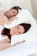 stressed future mom with head under the pillow in bed with her h