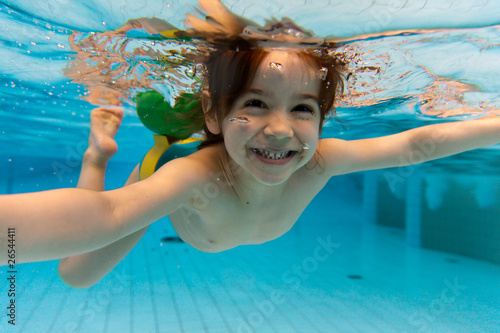 Photo : The girl smiles, swimming under water in the pool The girl smiles, swimming under water in the pool