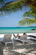 Man relaxing with beer in shadows under palm trees on the beach