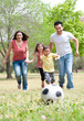 Foto: Parents and two young children playing soccer in the green field Parents and two young children playing soccer in the green field