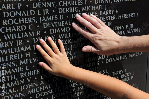 Photo: Hand of Adult and Child Touching Names at War Memorial Hand of Adult and Child Touching Names at War Memorial