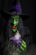 Scary witch holding a smoking goblet.