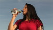 Below view of a woman drinking water with blue sky on background