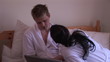 Young couple in bathrobe sitting with laptop in their bedroom