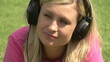 Video: Serious woman with headphones lying on the grass Serious woman with headphones lying on the grass