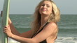 Seductive woman holding her surfboard standing on the beach