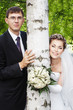 Foto: Happy smiling bride with groom outdoors next to birch tree Happy smiling bride with groom outdoors next to birch tree