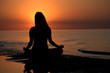 Silhouette of a woman doing yoga by the sunset on the beach Silhouette of a woman doing yoga by the sunset on the beach