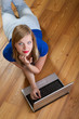 Pretty girl on a wooden floor relaxing and using a laptop