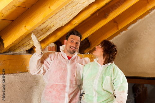 Photo: Couple installing thermal insulation to roof Couple installing thermal insulation to roof