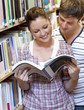 Two students enjoying reading a book together in the library Two students enjoying reading a book together in the library