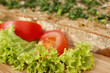 Eine Scheibe Brot auf einem Holzbrett mit Tomaten und Salat