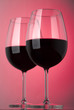 Two glasses of red wine on a pink background