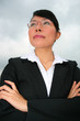 Asian business woman under a cloudy sky.