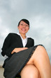 Asian business woman under a cloudy sky.
