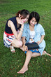 Two beautiful girl on a laptop computer outdoors. Lay on the gre Two beautiful girl on a laptop computer outdoors. Lay on the gre