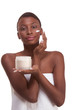 Black woman wrapped in towel moisturizing face Black woman wrapped in towel moisturizing face