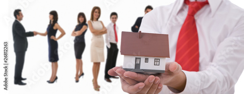 Foto: Businesspeople shaking hands and posing with dummy of house Businesspeople shaking hands and posing with dummy of house