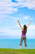 A beautiful young woman standing with her arms up in the air loo