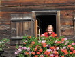 Frau an Fenster an altem Bauernhaus