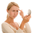 Woman finding an acne on her forehead