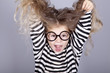 Young shouting child in glasses and striped knitted jacket.
