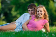 A couple relaxing in the park, lying on the grass, lit in the ev A couple relaxing in the park, lying on the grass, lit in the ev