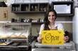 Happy owner of a café showing open sign