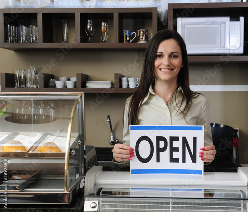 Photo: Happy owner of a café showing open sign Happy owner of a café showing open sign