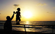 silhouettes of father and son on sunset sea background