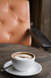 A cup of Cappuccino with orange armchair background