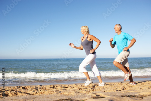 Photo: Senior Couple In Fitness Clothing Running Along Beach Senior Couple In Fitness Clothing Running Along Beach
