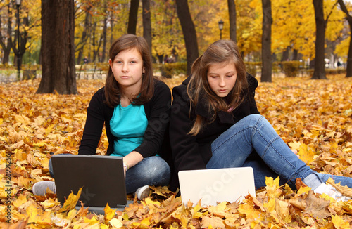 Photo: teenagers with a computer in the autumn park teenagers with a computer in the autumn park