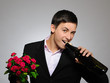 Foto: Handsome romantic young man holding rose flower and vine bottle Handsome romantic young man holding rose flower and vine bottle