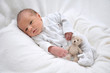 Foto: Baby mit Stofftier im weißen Bett Baby mit Stofftier im weißen Bett