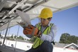 Photo: Maintenance worker refers to notes under solar panel in Los Angeles, California Maintenance worker refers to notes under solar panel in Los Angeles, California