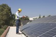 Photo: Maintenance worker stands with solar array on rooftop, Los Angeles, California Maintenance worker stands with solar array on rooftop, Los Angeles, California