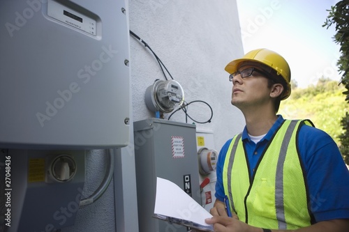Photo: Maintenance worker reads meter of solar generation unit in Los Angeles, California Maintenance worker reads meter of solar generation unit in Los Angeles, California