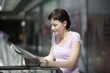 Young woman reading newspaper in shopping centre, Voronezh