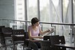 Young woman sits reading newspaper in food hall of shopping mall, Voronezh
