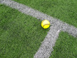 Yellow Softball sitting on Astroturf