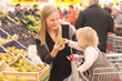 young mother and toddler girl shopping pear in supermarket