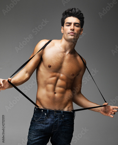 Photo: Sexy macho man wearing suspender against grey background Sexy macho man wearing suspender against grey background