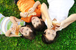 Three children laying on grass on ground, eating
