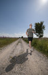 Foto: Athletic male running on field road on hot summer day. Athletic male running on field road on hot summer day.