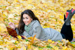 Happy student girl lying in autumn leaves with netbook Happy student girl lying in autumn leaves with netbook
