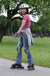 Young woman learning to ride on rollerblades in the park.